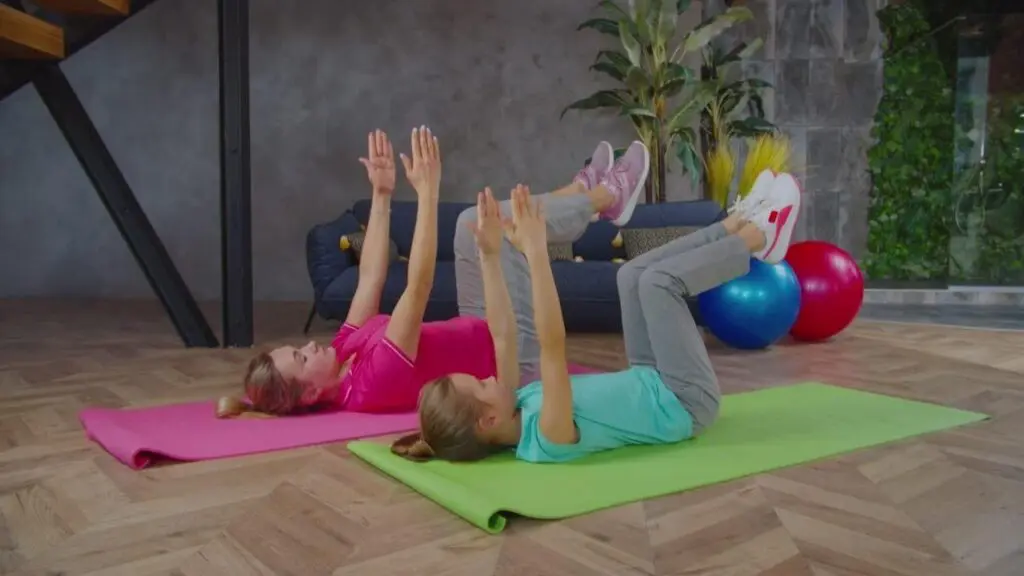 two women performing a dead bug core exercise beside each other.