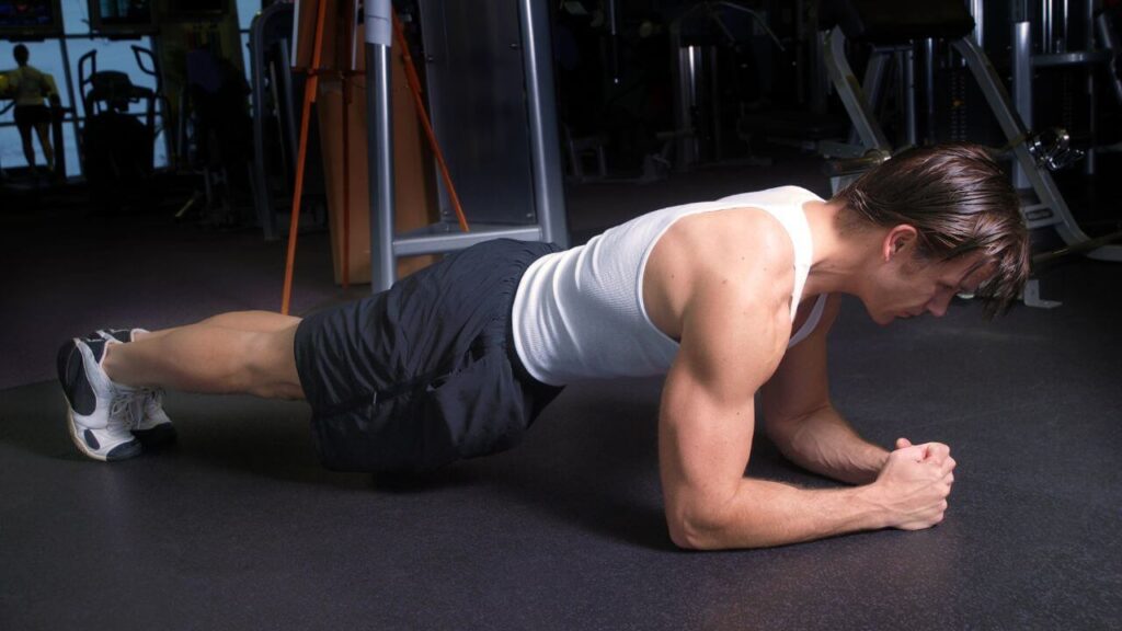 Man performs front plank it the gym