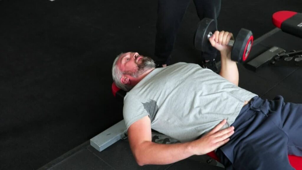 Man performing one-arm dumbbell bench press 