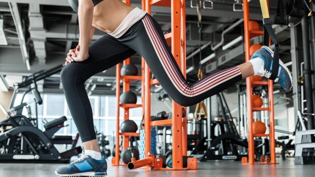 Woman performs rear foot elevated split squats in the commercial gym