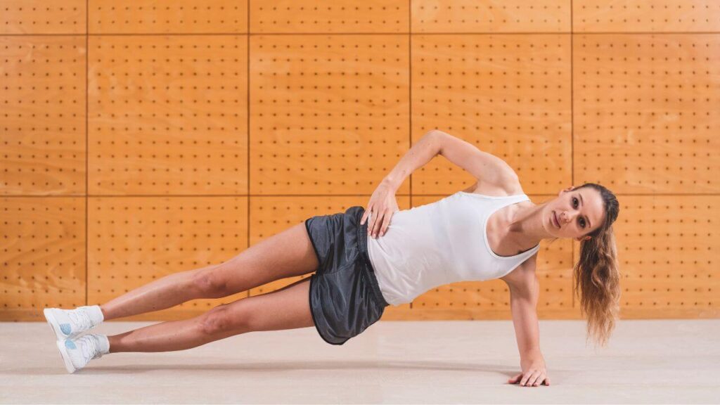 woman performs side plank on her left elbow