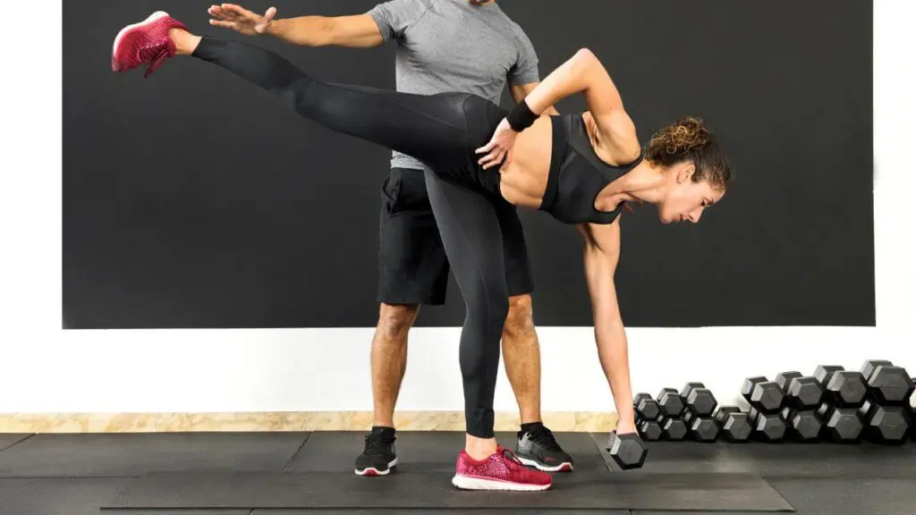 woman performing single leg deadlift with the help of a partner