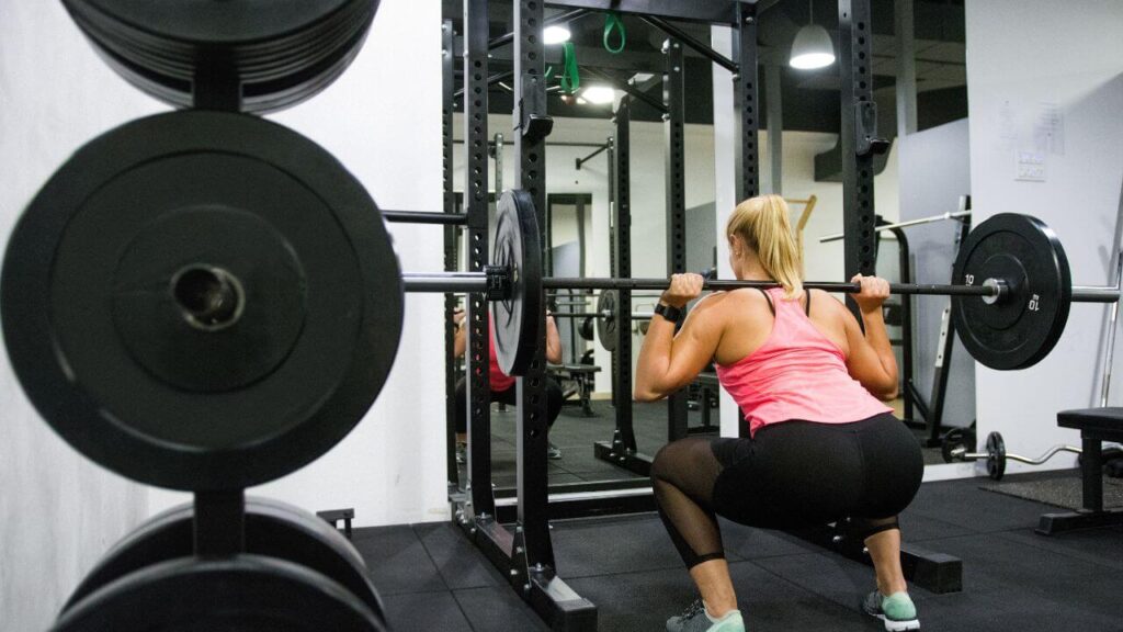 Woman squatting in front of a squat rack