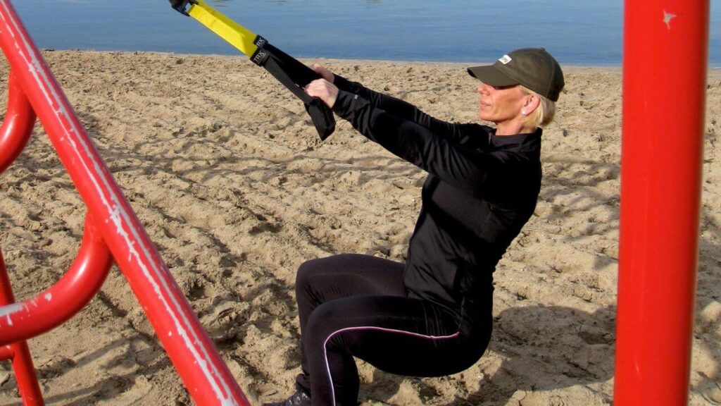 woman performing TRX rows outside 