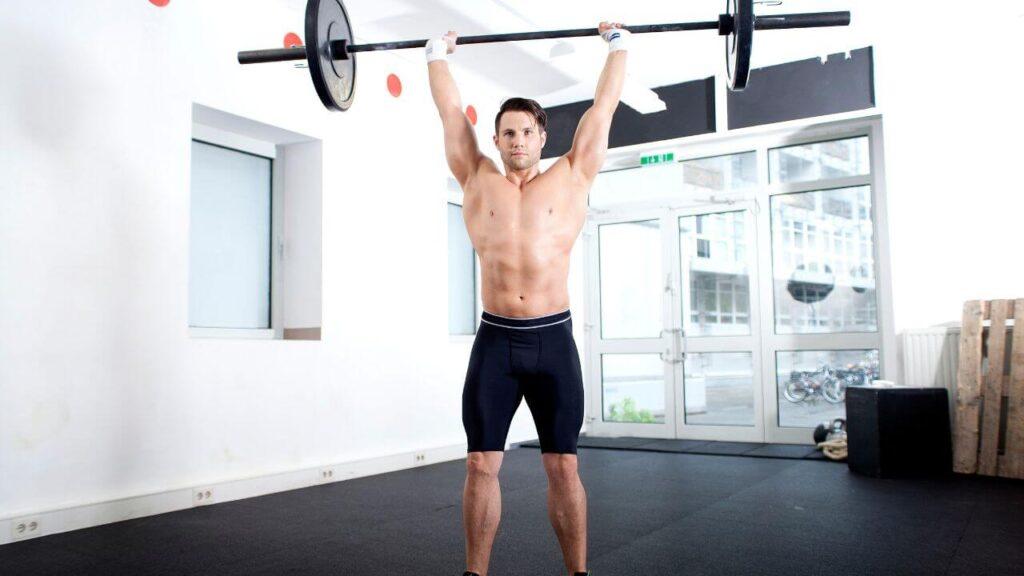 A man demonstrates proper barbell overhead press technique and how to hold the barbell in the top position while remaining stable and without excessive tilt in the hips.