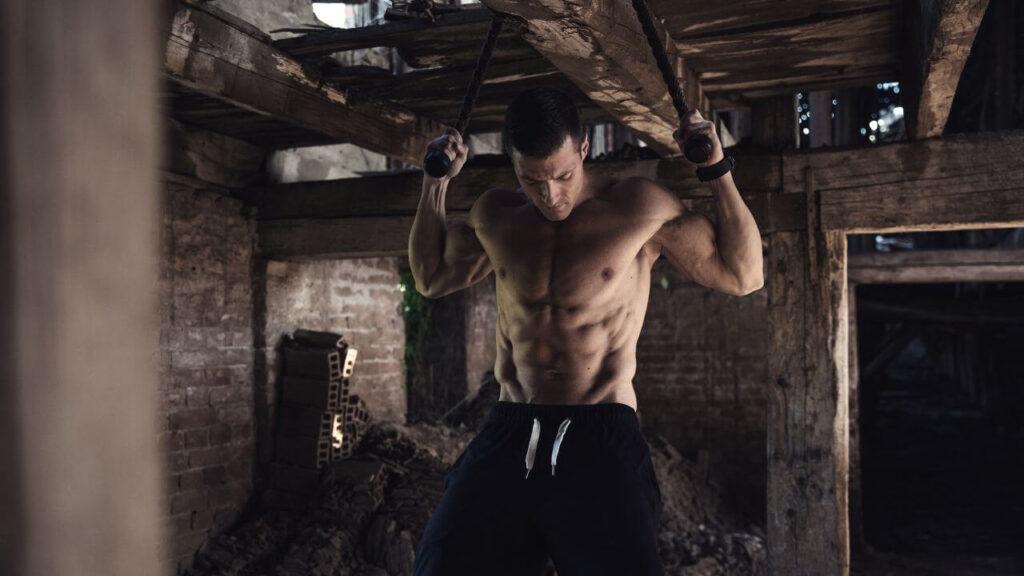 Man performs pull ups with ropes, but that can also be done the same way with the towel.