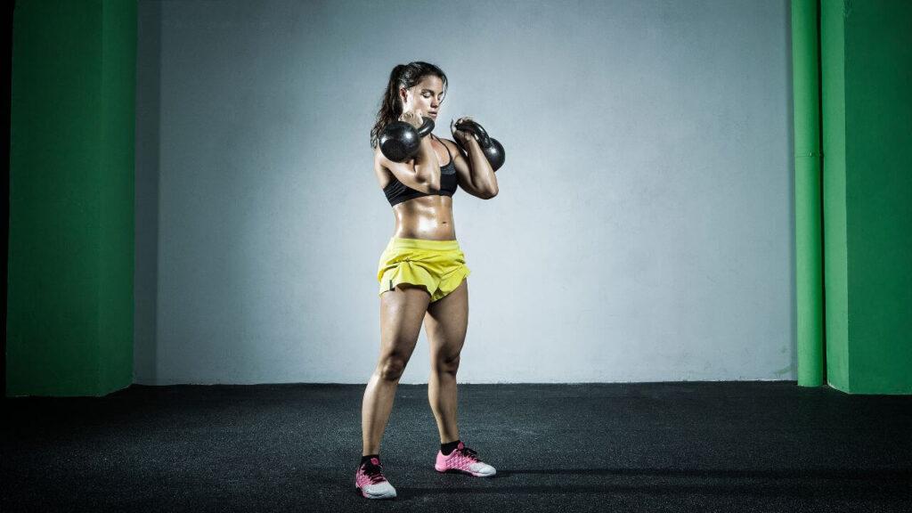 Woman performing kettlebell clean and press exercise.