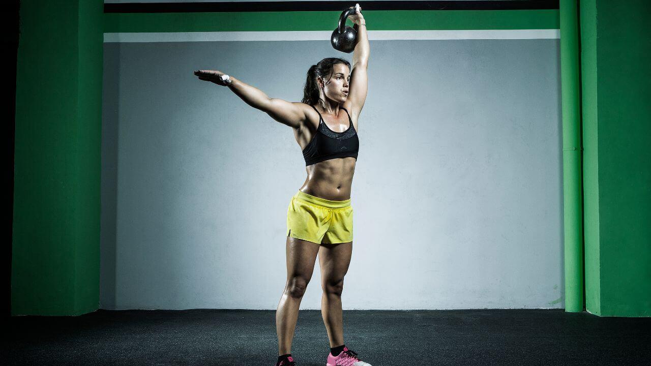 Woman performs one-arm kettlebell snatch