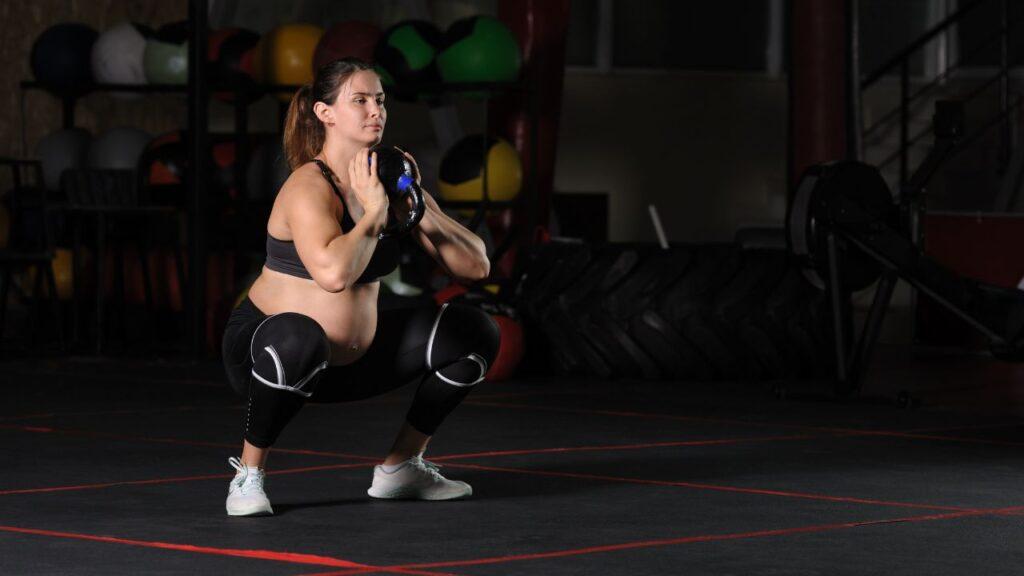 A woman performing kettlebell goblet squats in the gym