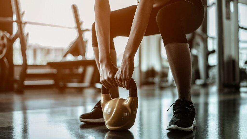 A woman performs kettlebell deadlift in the gym