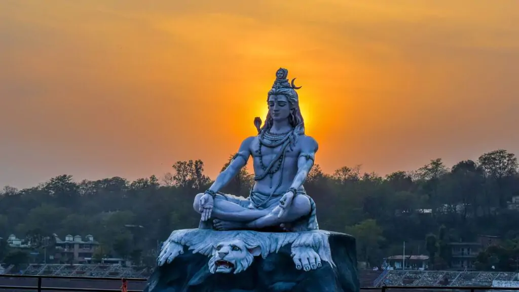 Shiva, Indian God of destruction sitting in the cross-legged stance, meditating in the beautiful sunset.