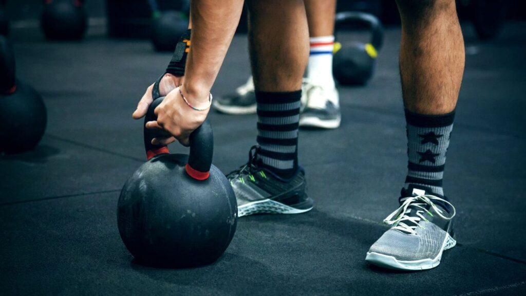 Man holds a competition kettlebell in a commercial gym.