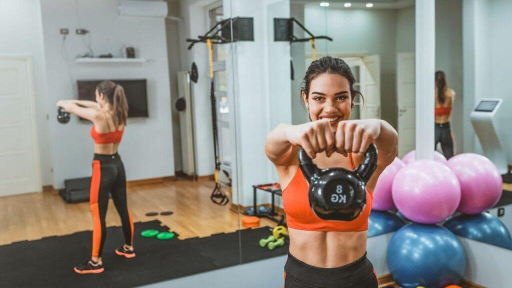 A woman holds a kettlebell with both of her hands.