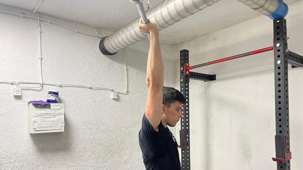 Vanja performs push press shoulder exercise in a commercial gym.
