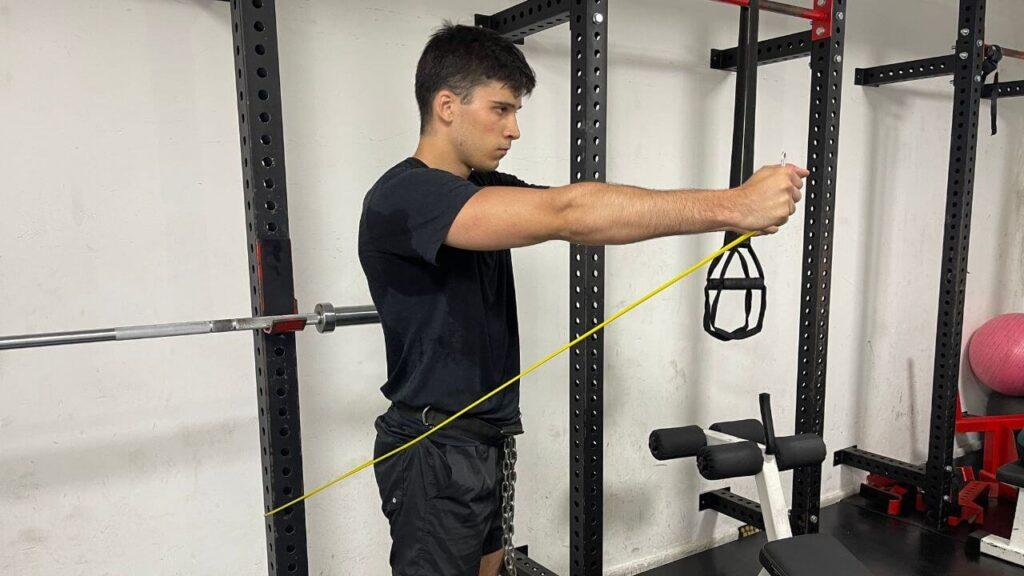 Vanja performs resistance band front raise and lateral raise in the commercial gym.