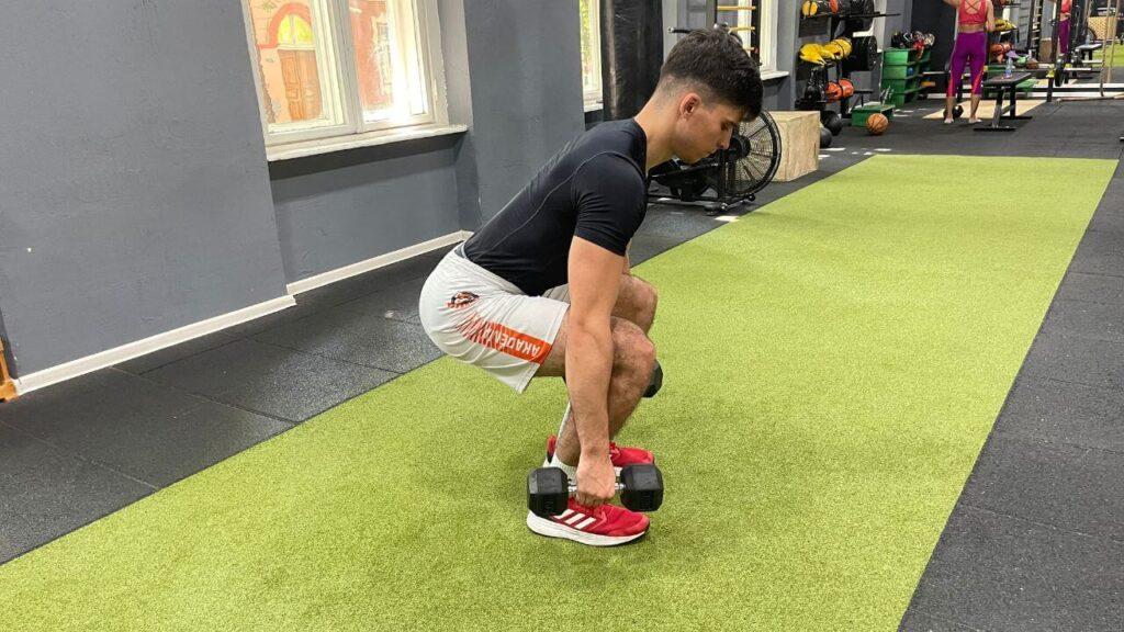 Vanja performs dumbbell squats in the commercial gym setup.