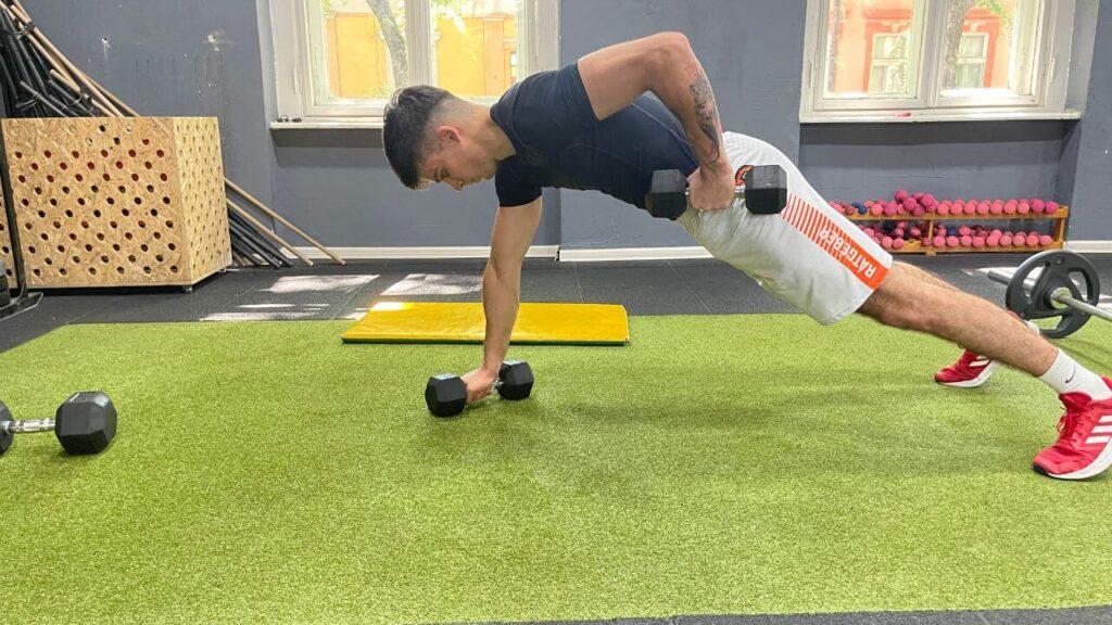 Vanja performs renegade rows with dumbbells.