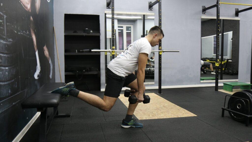 Radomir performs Bulgarian split squats with dumbbells.