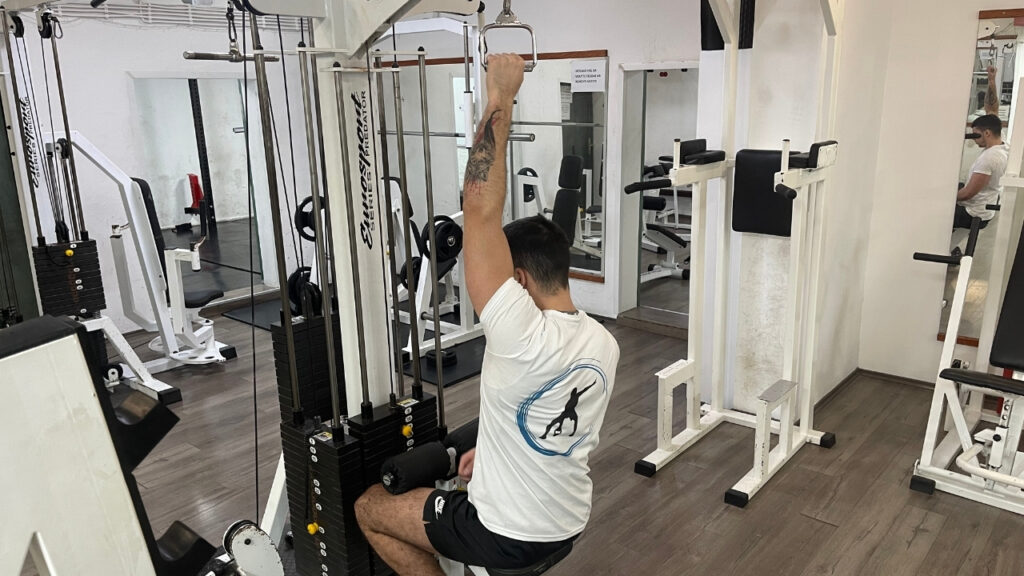 Vanja assumes the starting position on the lat pulldown machine.